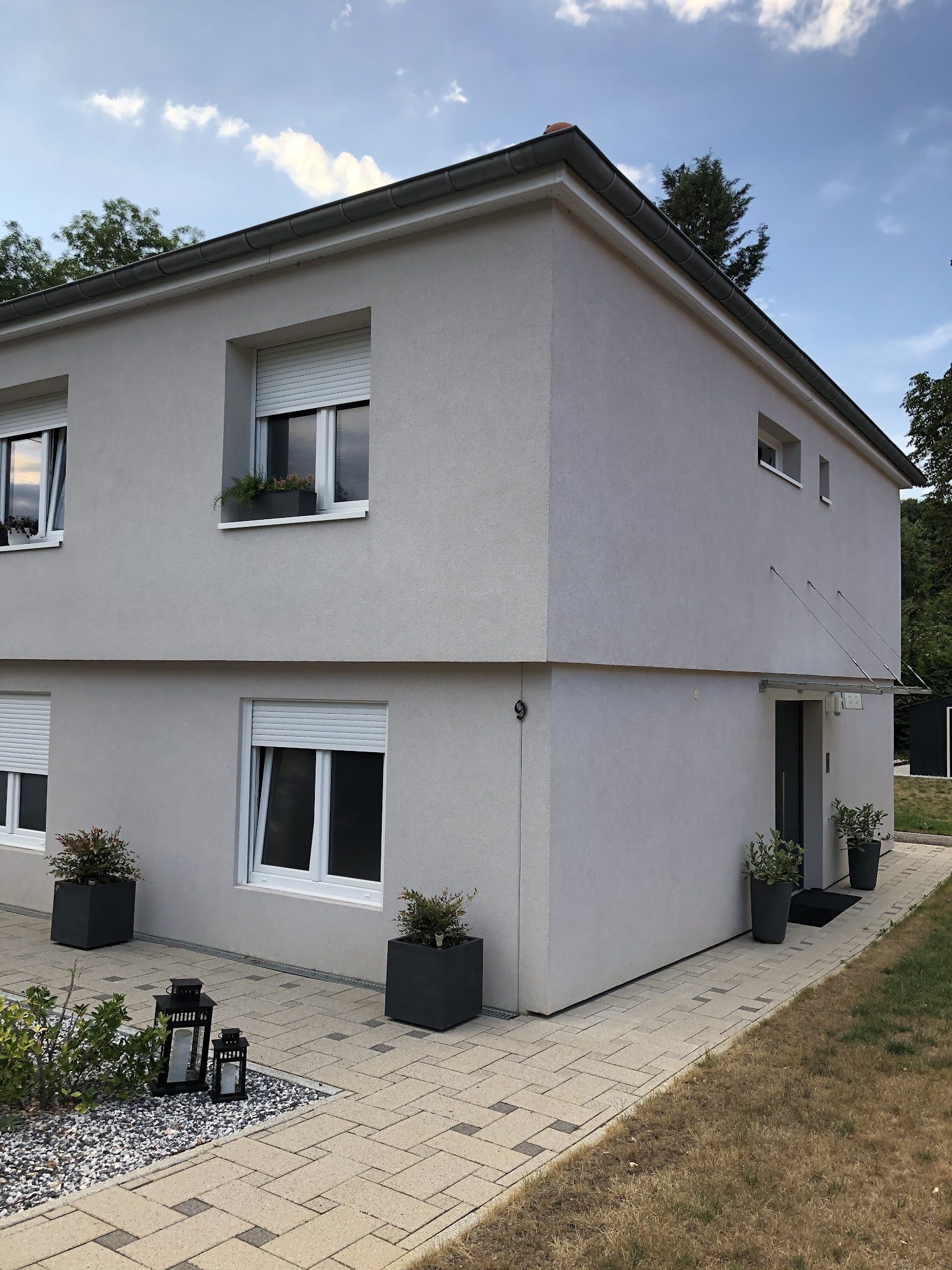 Maison au crépi gris clair après ravalement et isolation par l'extérieur