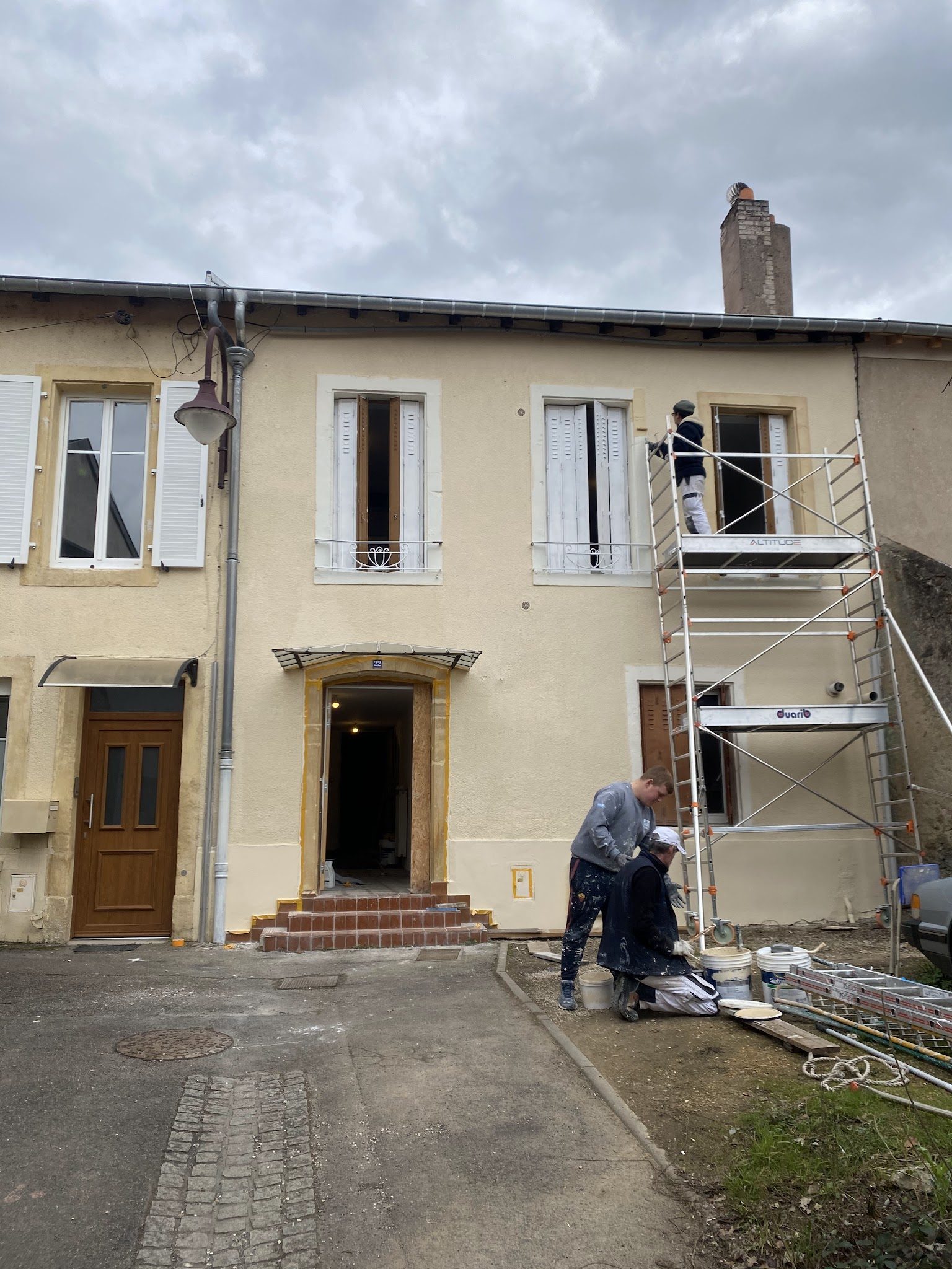 L'équipe SLTB en plein ravalement d'une façade, échafaudage roulant et seaux d'enduit