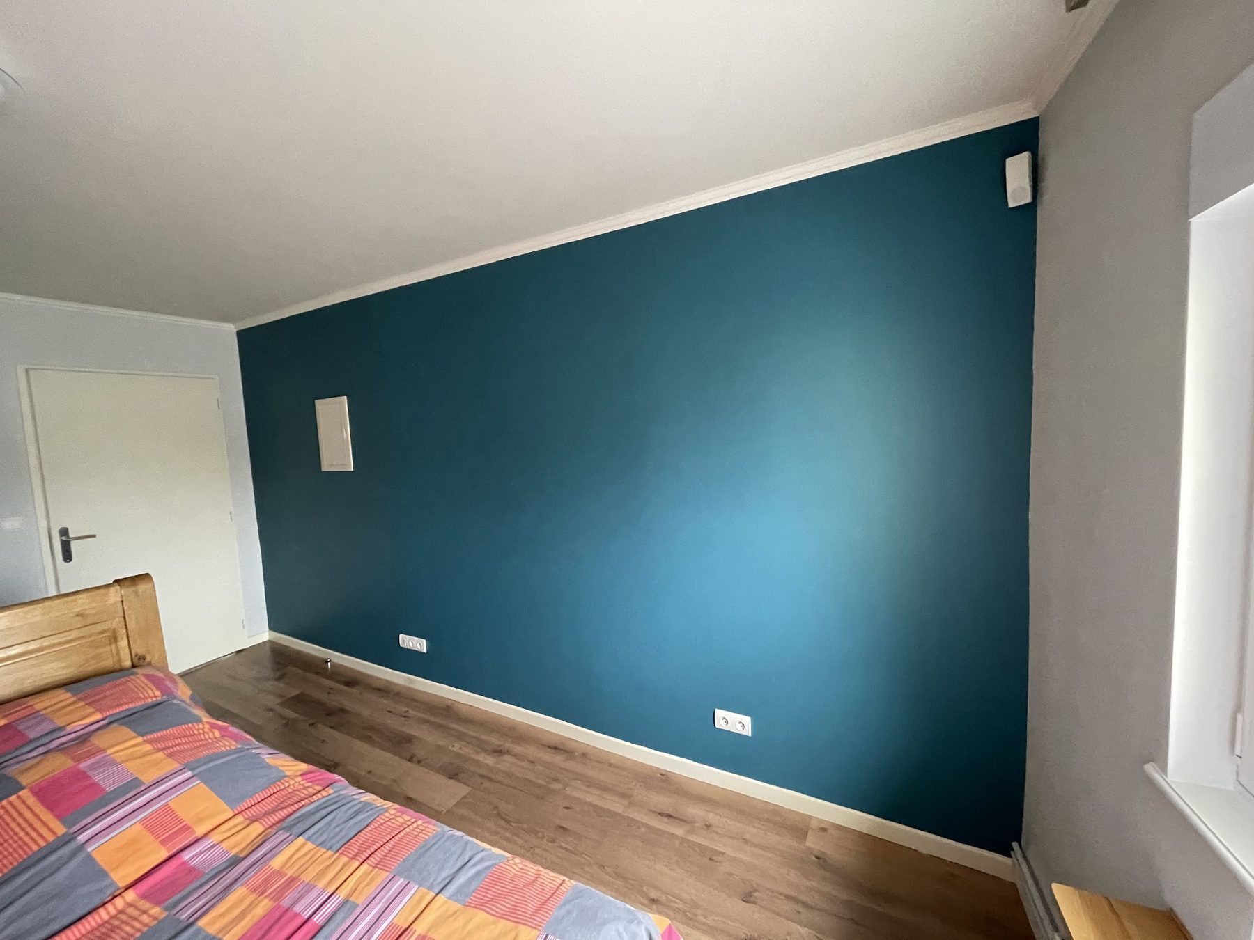 Chambre avec un mur peint en bleu canard
